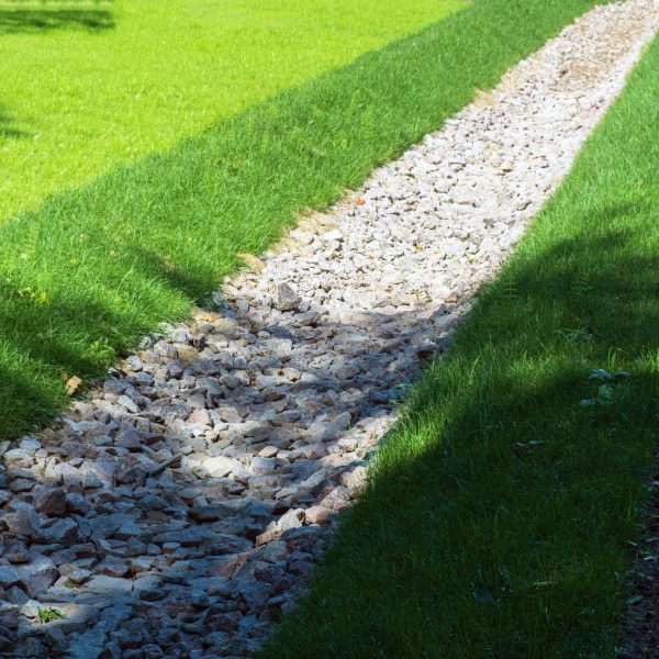 drainage, a drainage system in a Park area, a waterway overgrown with lawn and paved with stones, an Aqueduct between nature and the road. stone water drains in a grass garden field. Lawn and plant protection.